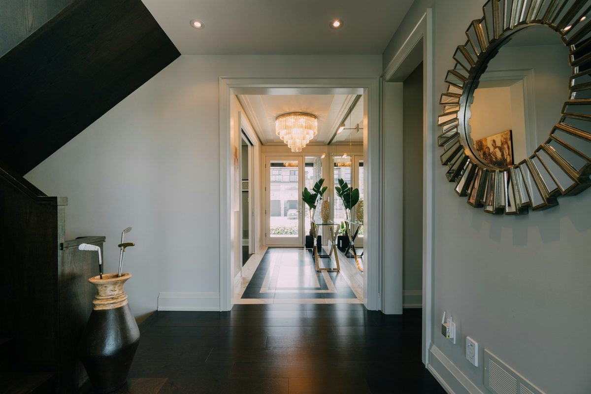 Refined entryway hall with a chandelier, sunburst mirror, and paneled walls.
